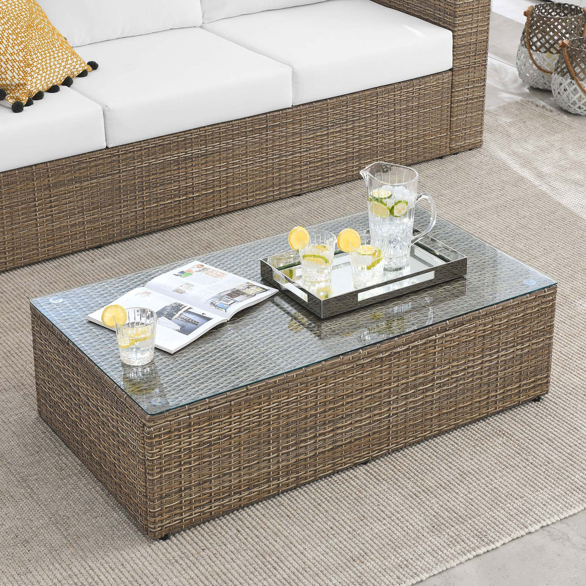 Brown wicker outdoor coffee table with glass top paired with matching sectional seating on patio || EEI-6239 || front_angle_room