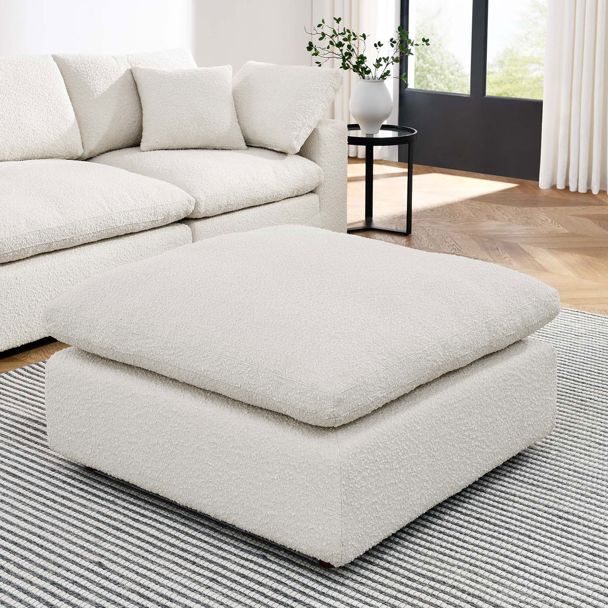 Commix ivory boucle ottoman centered in a modern living room, offering plush comfort and inviting texture. || EEI-6258-IVO || front_angle_room