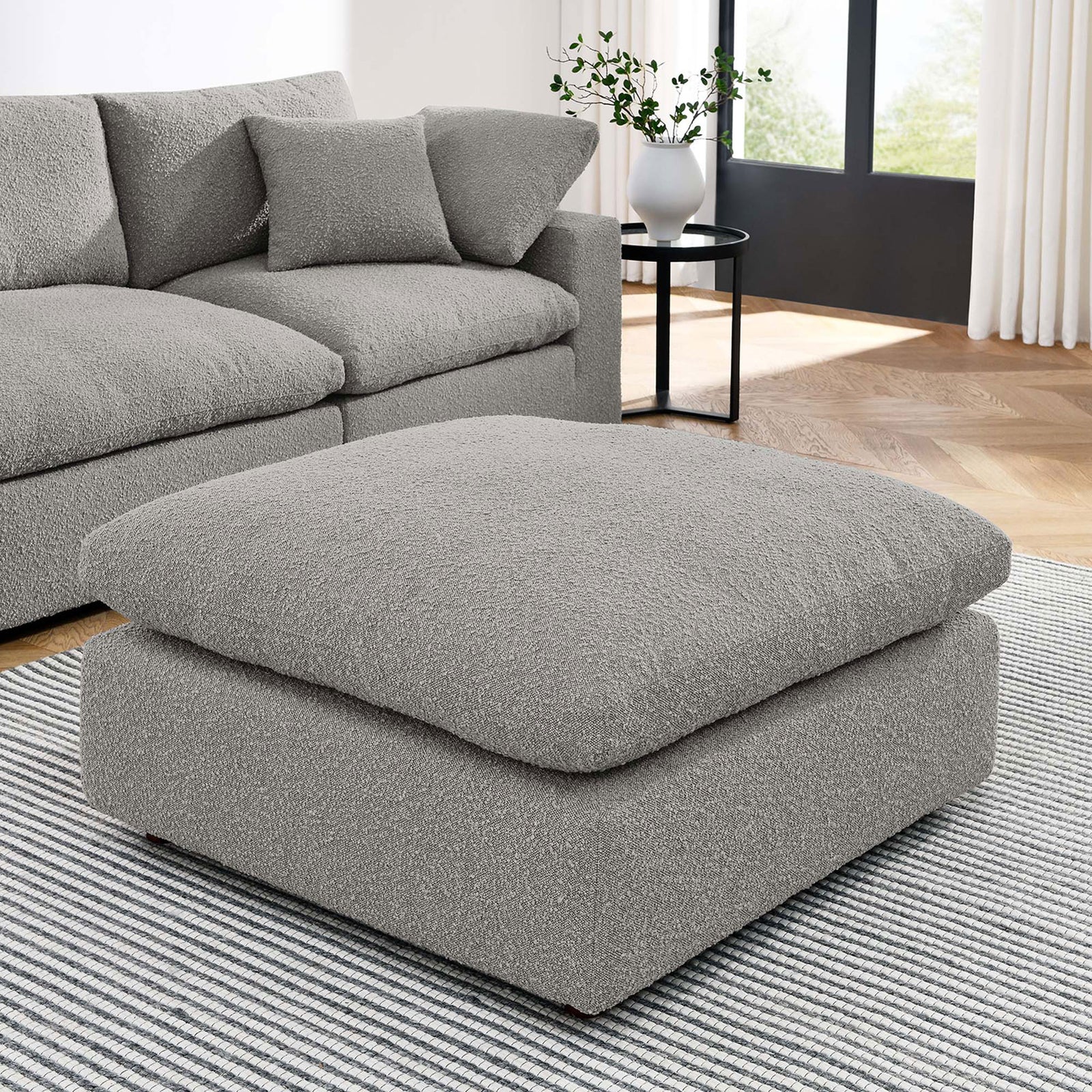 Light gray boucle ottoman anchors an airy living room, offering extra seating or a plush surface to stretch out || EEI-6258-LGR || front_angle_room