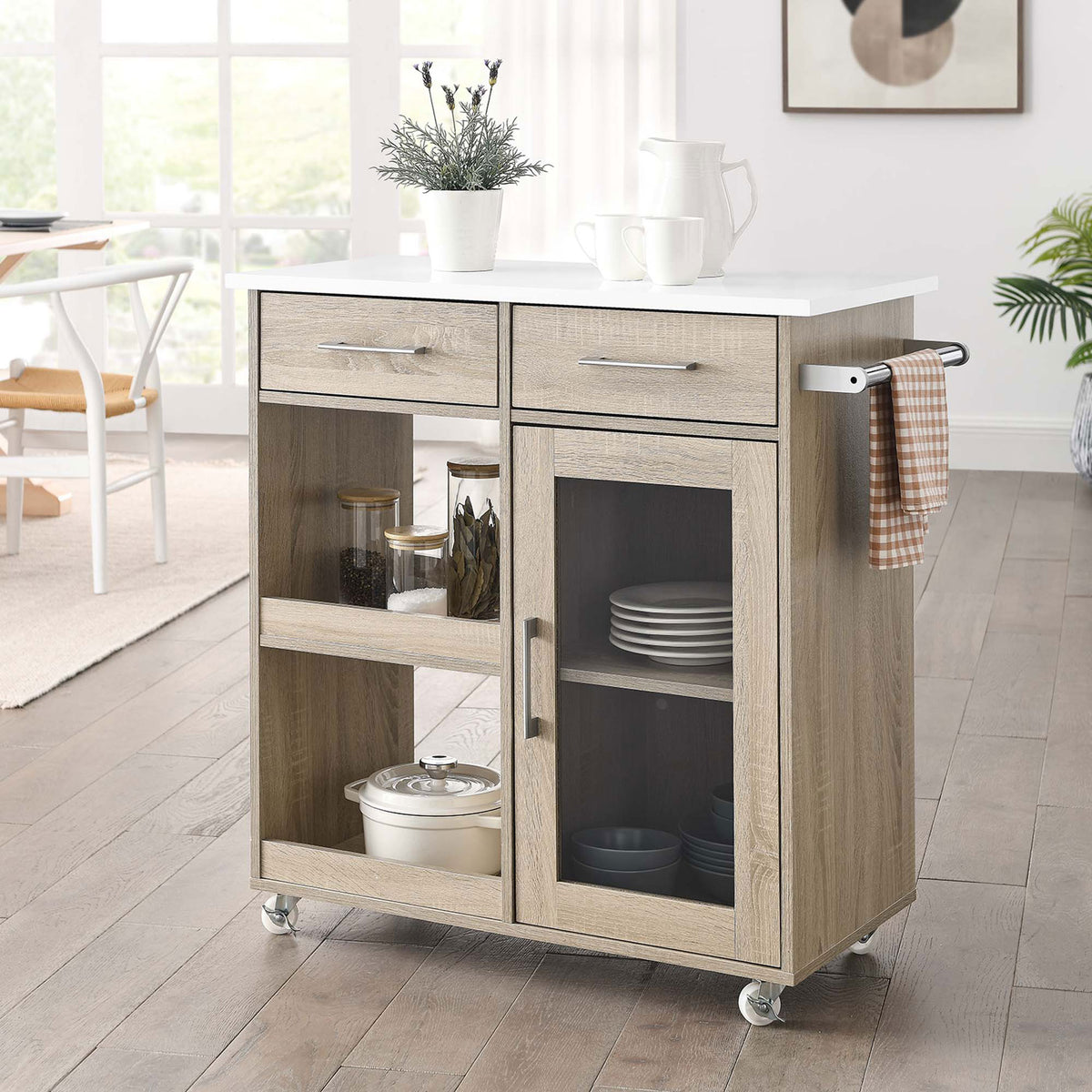 Oak and white kitchen cart styled in a bright dining space with open shelves, glass-door cabinet, and side towel bar || EEI-6275-OAK-WHI || front_angle_room