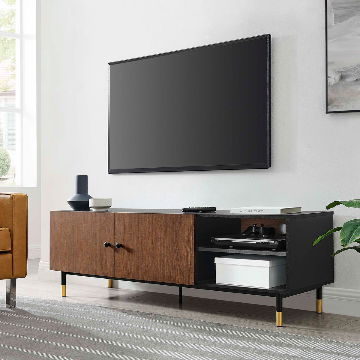 Nexus TV stand in a modern living room holding media components beneath a wall mounted TV || EEI-6282-BLK-WAL || front_angle_room