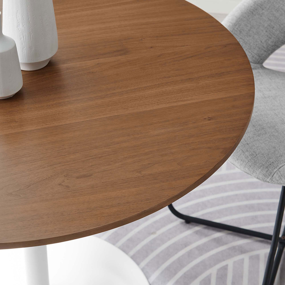 Close-up of walnut tabletop in a stylish dining setting with soft gray seating and a patterned rug || EEI-6313-WAL-WHI || detail_room