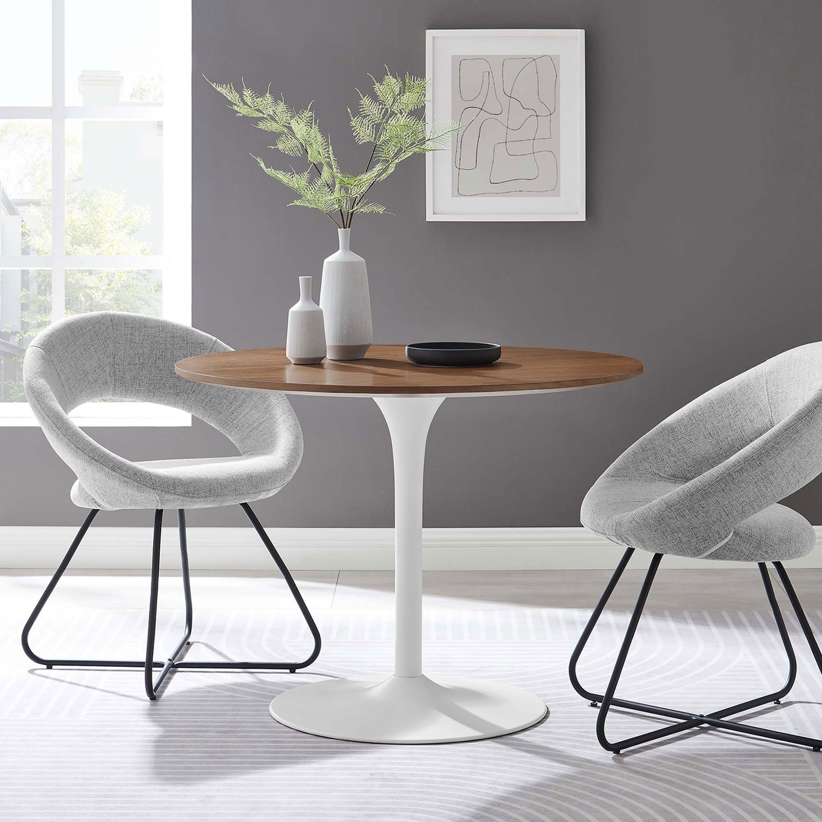 Round walnut and white pedestal dining table styled in a bright modern room with coordinating gray chairs || EEI-6313-WAL-WHI || front_angle_room