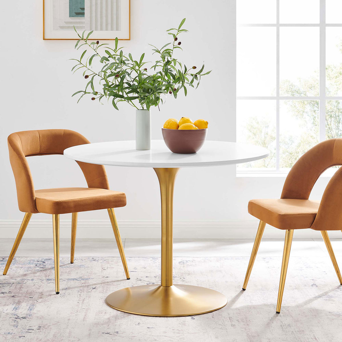 Round white dining table with gold pedestal base styled in a bright, contemporary breakfast nook || EEI-6313-WHI-GLD || front_angle_room