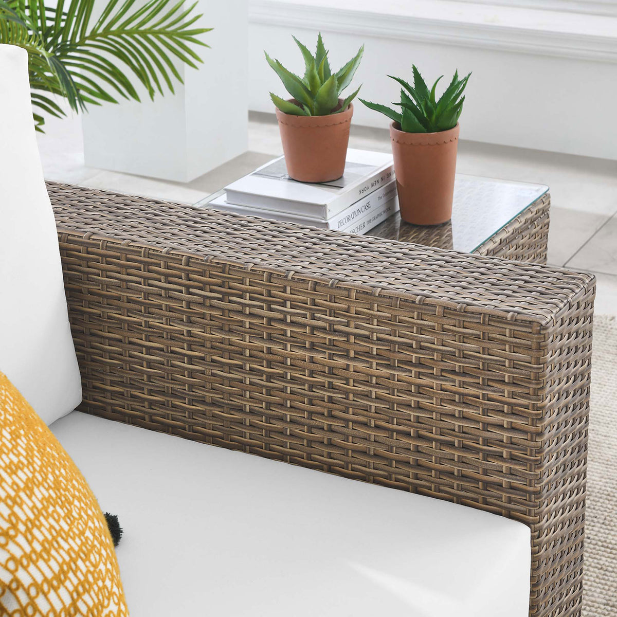 Cappuccino wicker armrest with white cushion styled beside greenery and a glass side table || EEI-6326-CAP-WHI || detail_room
