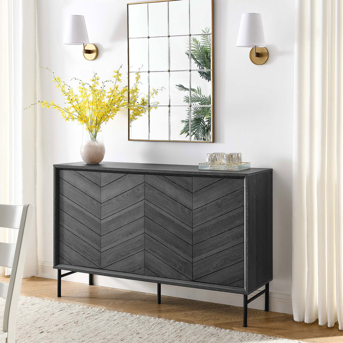 Black chevron sideboard in a bright dining space, topped with mirror, florals, and entertaining essentials || EEI-6336-BLK || front_angle_room
