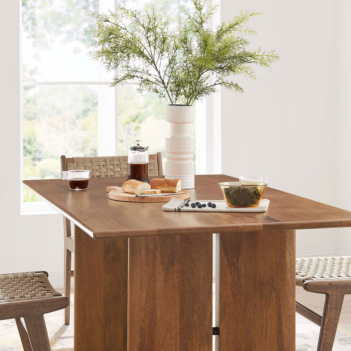 Tabletop corner of the Amistad dining table styled with pastries tea and woven chairs || EEI-6338-WAL || detail_room