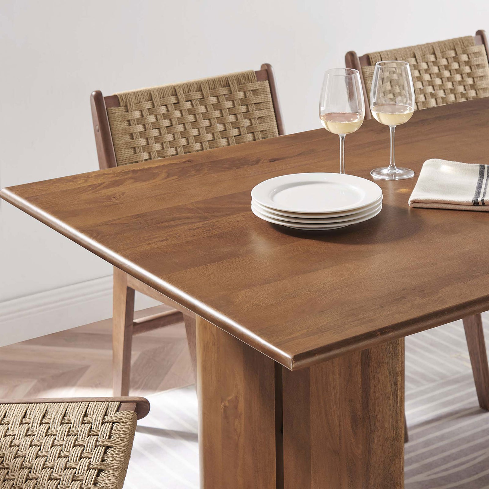 Amistad dining table corner styled with plates wine glasses and woven dining chairs || EEI-6339-WAL || detail_room
