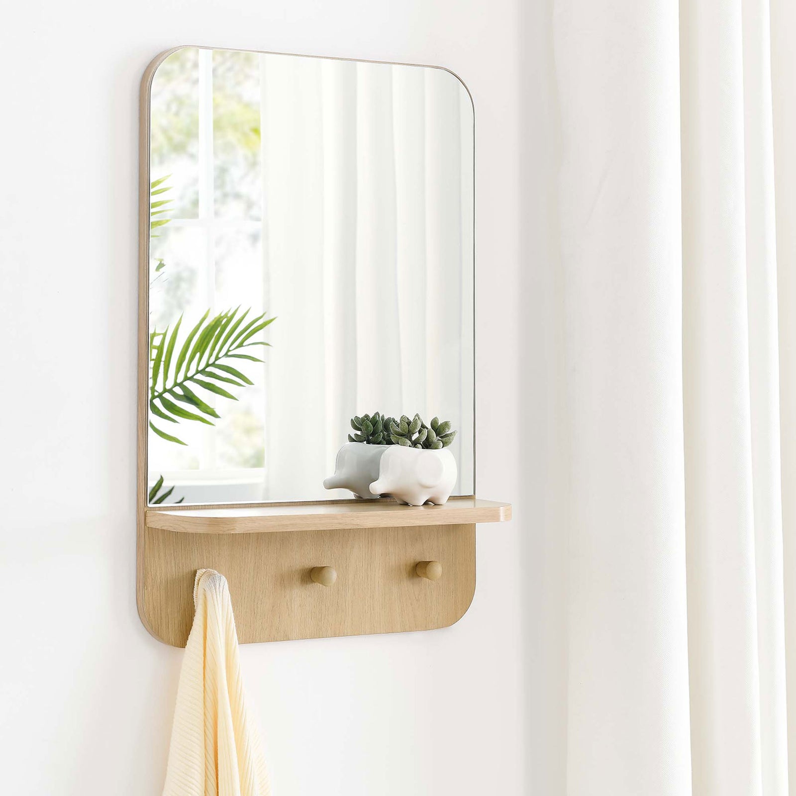 Lumina oak wall mirror styled in a bright entryway with towel and decor on the integrated shelf || EEI-6348-OAK || front_room