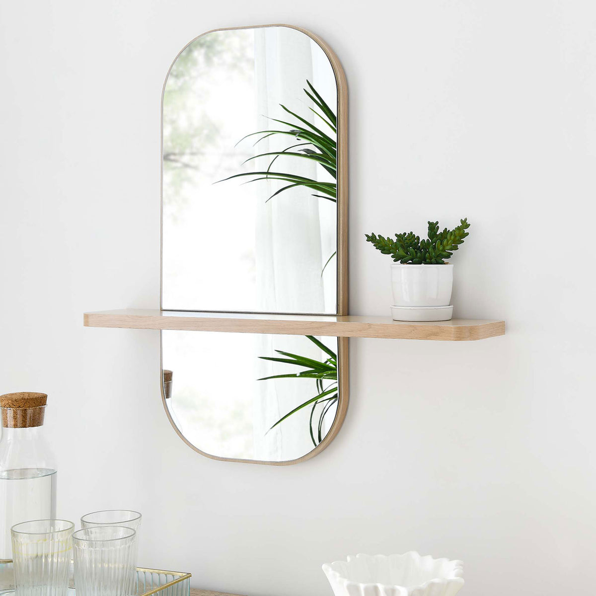 Oak wall mirror with shelf holding a small plant, adding warmth and storage to modern decor. || EEI-6349-OAK || front_angle_room