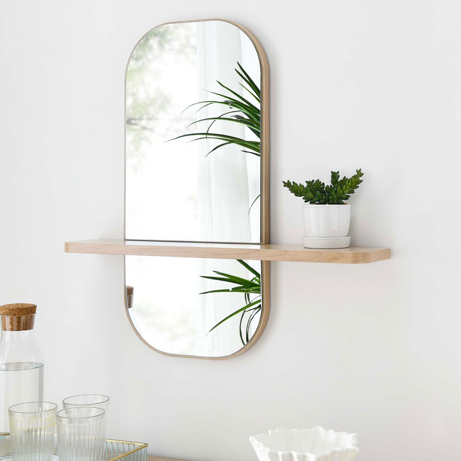 Oak wall mirror with shelf holding a small plant, adding warmth and storage to modern decor. || EEI-6349-OAK || front_angle_room