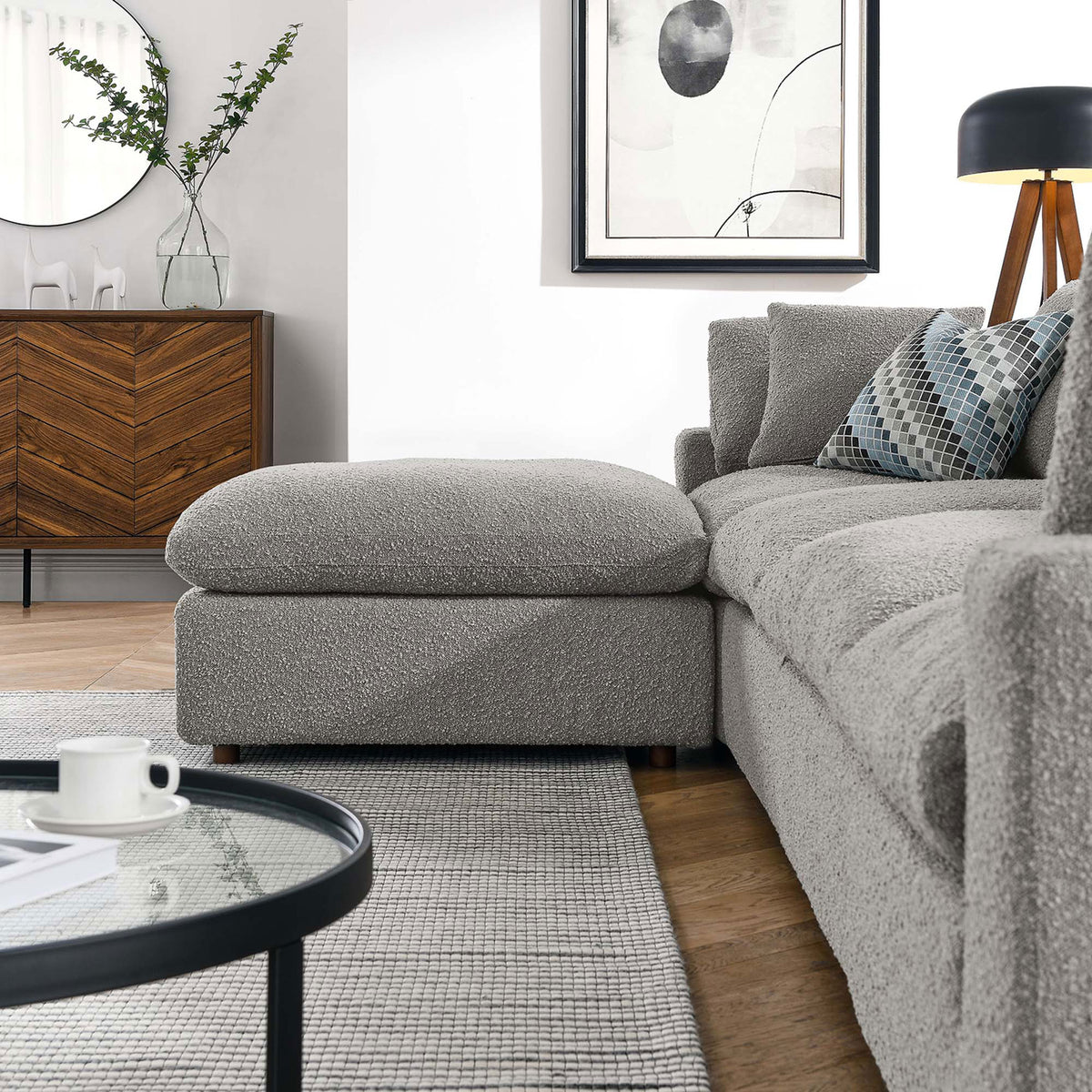 Ottoman and sofa arm in a modern living room styled with neutral rug, wood credenza, and decor. || EEI-6365-LGR || front_angle_partial_room