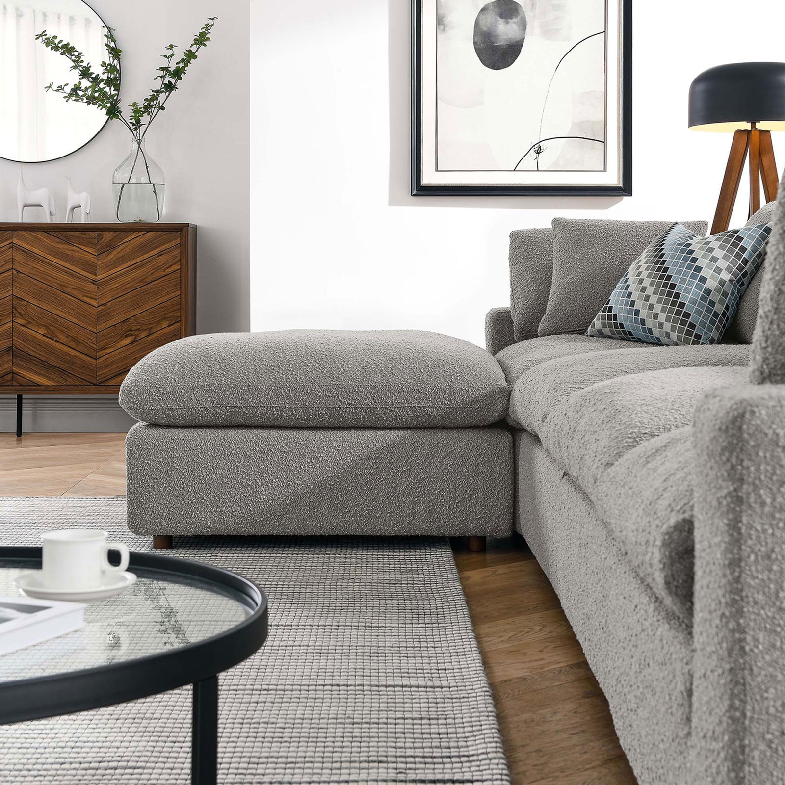 Ottoman and sofa arm in a modern living room styled with neutral rug, wood credenza, and decor. || EEI-6365-LGR || front_angle_partial_room