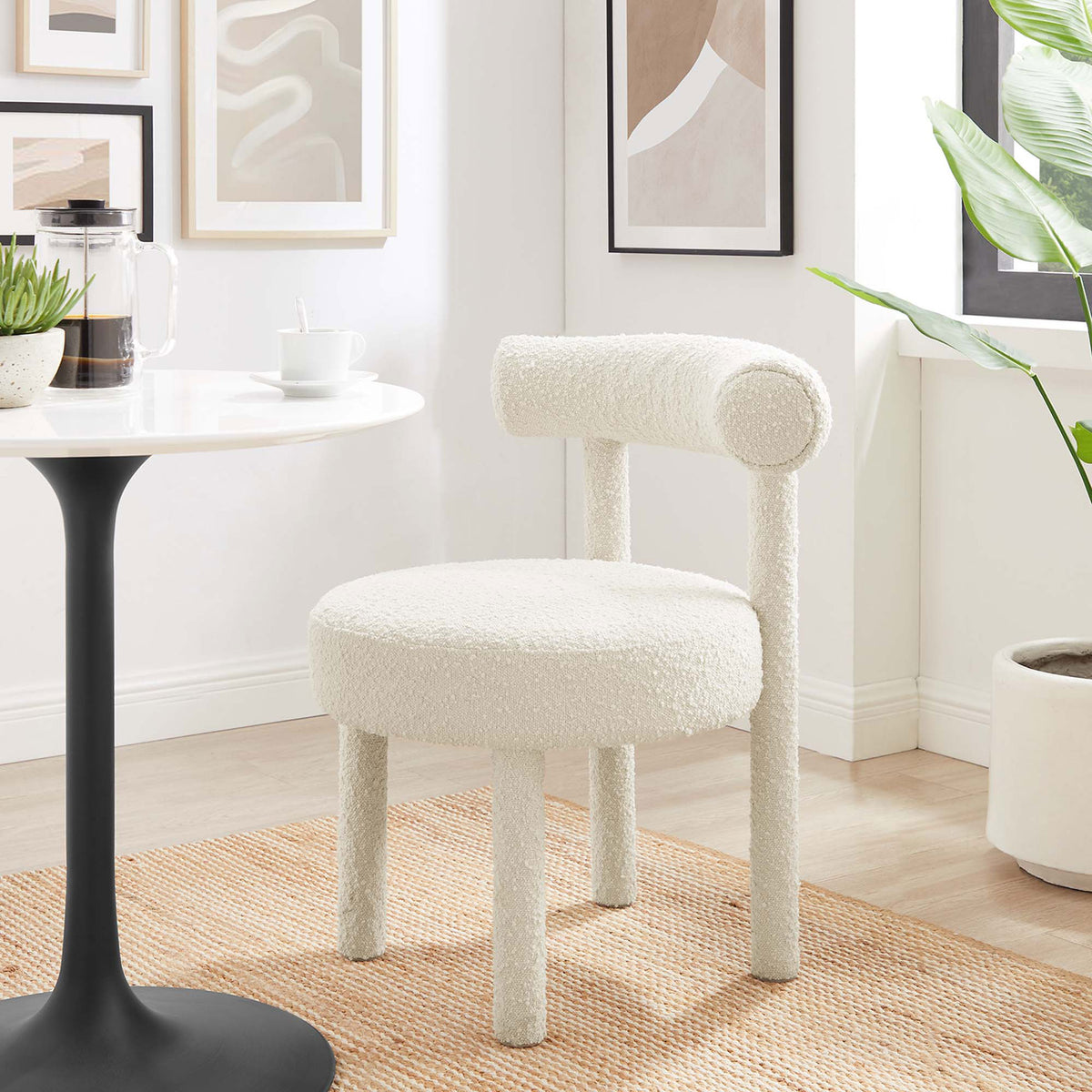 Ivory boucle dining chair styled in a bright dining nook with wall art, greenery, and a modern pedestal table || EEI-6387-IVO || front_angle_room