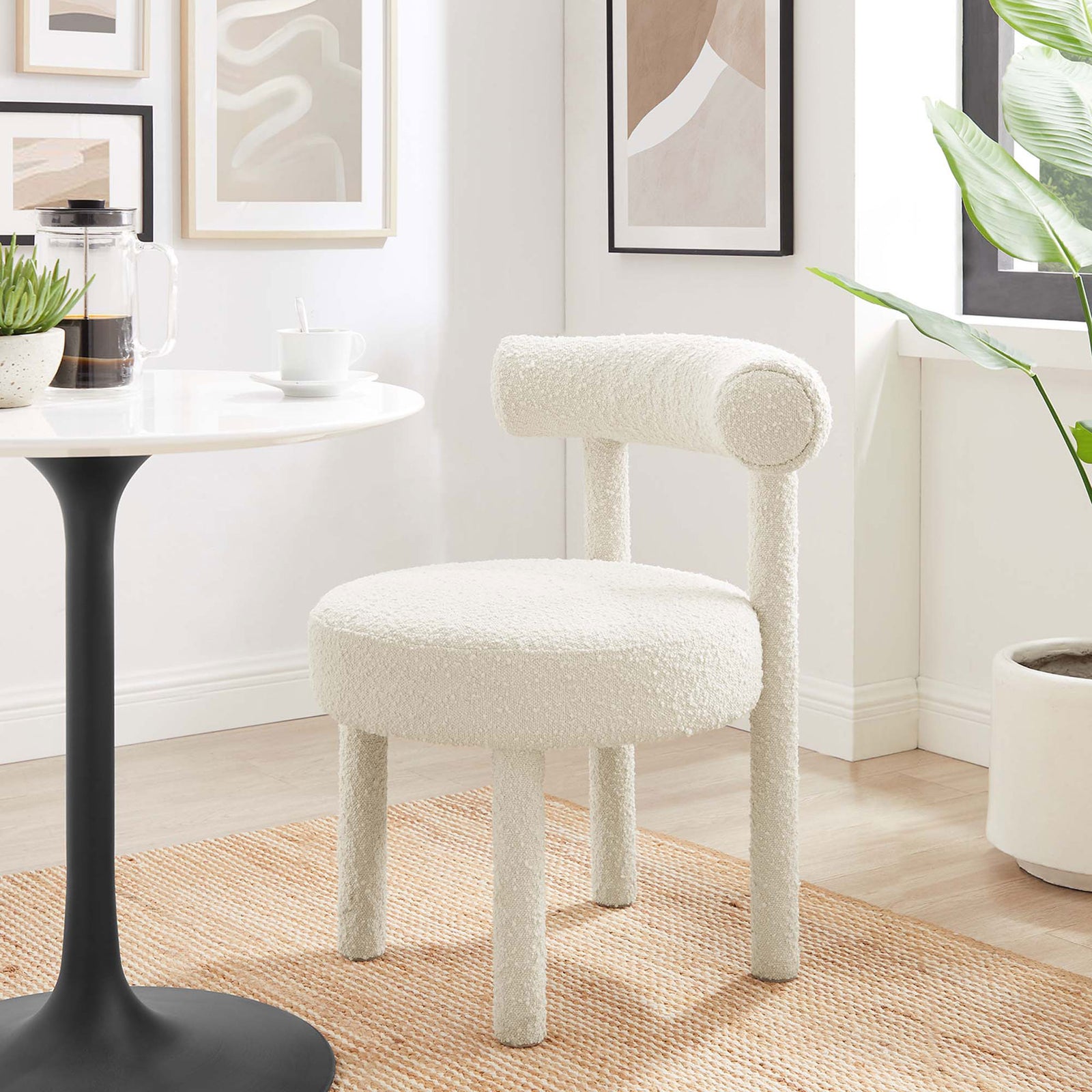 Ivory boucle dining chair styled in a bright dining nook with wall art, greenery, and a modern pedestal table || EEI-6387-IVO || front_angle_room