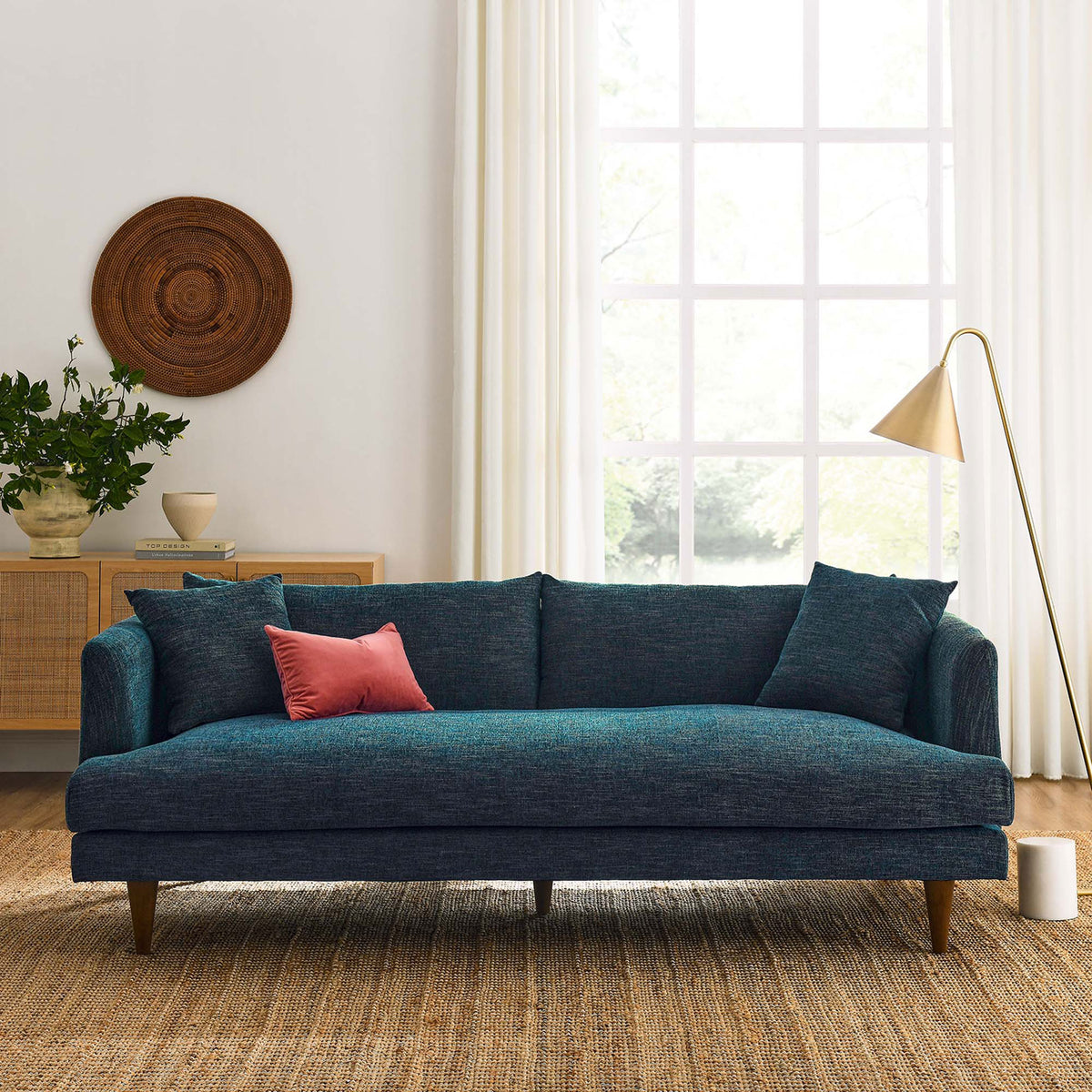 Zoya navy upholstered sofa styled in a sunlit living room with tapered wood legs, jute rug, and soft neutral decor || EEI-6405-HEA || front_room