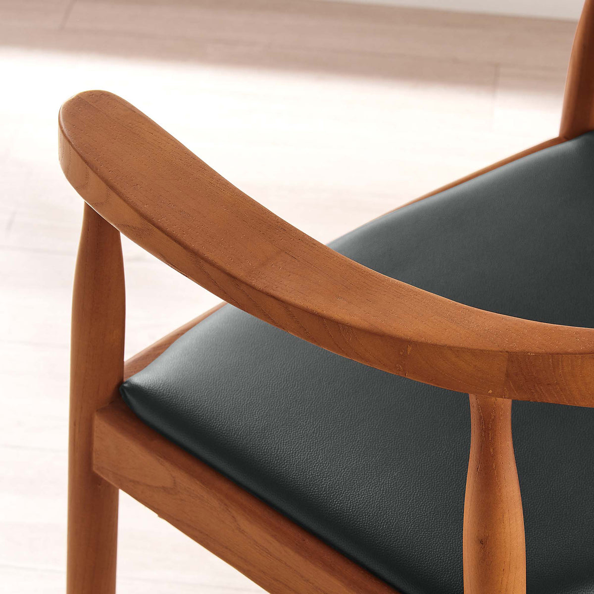 A rounded wood arm flows into slim supports alongside the black padded seat