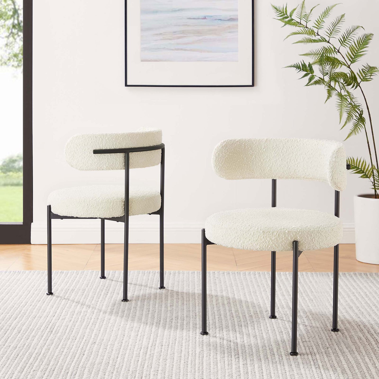 Set of two ivory boucle dining chairs with black legs styled in a bright, airy contemporary dining room. || EEI-6516-IVO-BLK || front_angle_multi_room