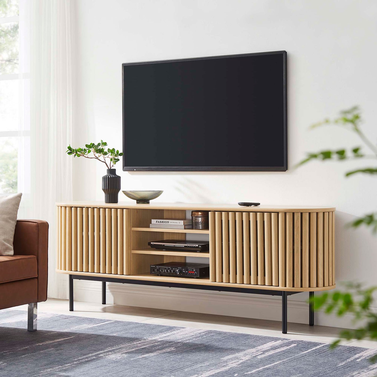Oak Fortitude TV stand anchoring a contemporary living room with streamlined oval form and airy black metal base || EEI-6522-OAK || front_room