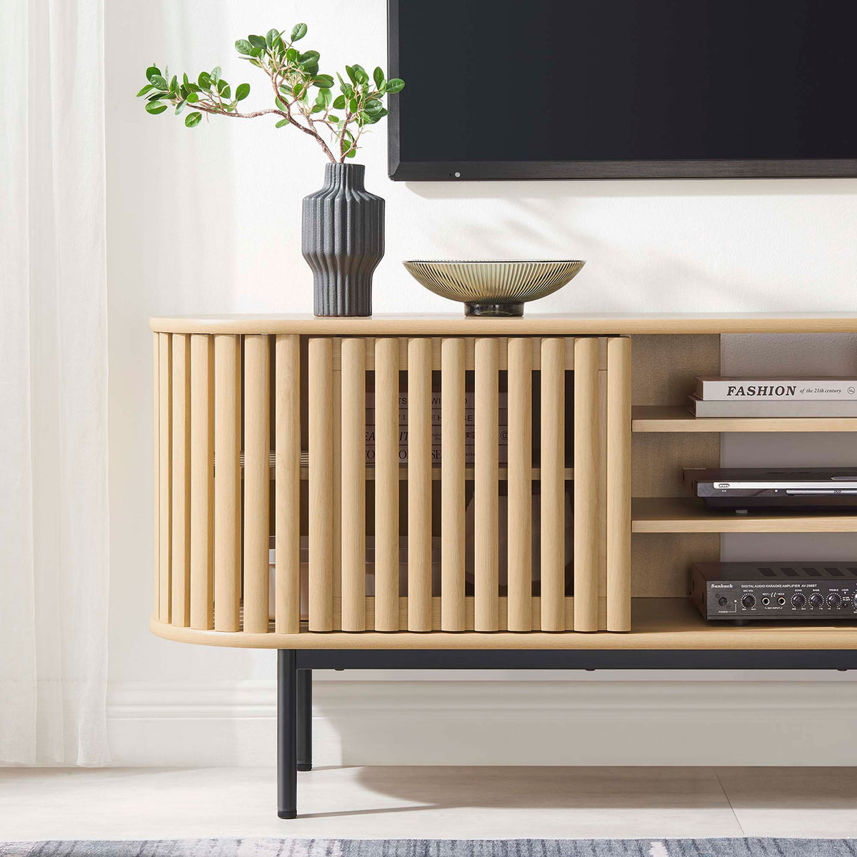 Oak TV stand styled with media components and decor beneath a wall mounted television in a bright living room || EEI-6522-OAK || detail_room