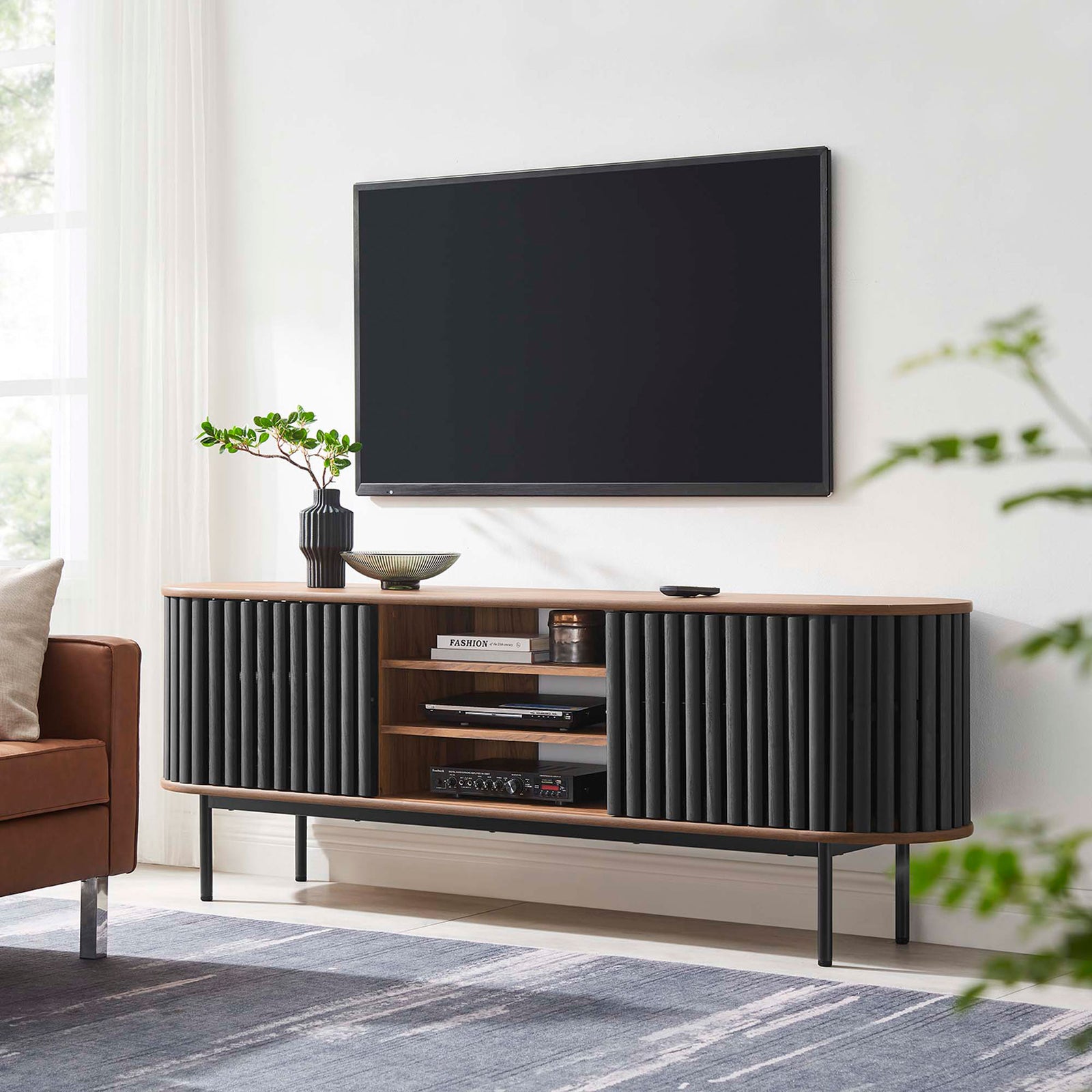 Walnut and black Fortitude TV stand anchoring a modern living room with its oval form and airy base || EEI-6522-WAL-BLK || front_room