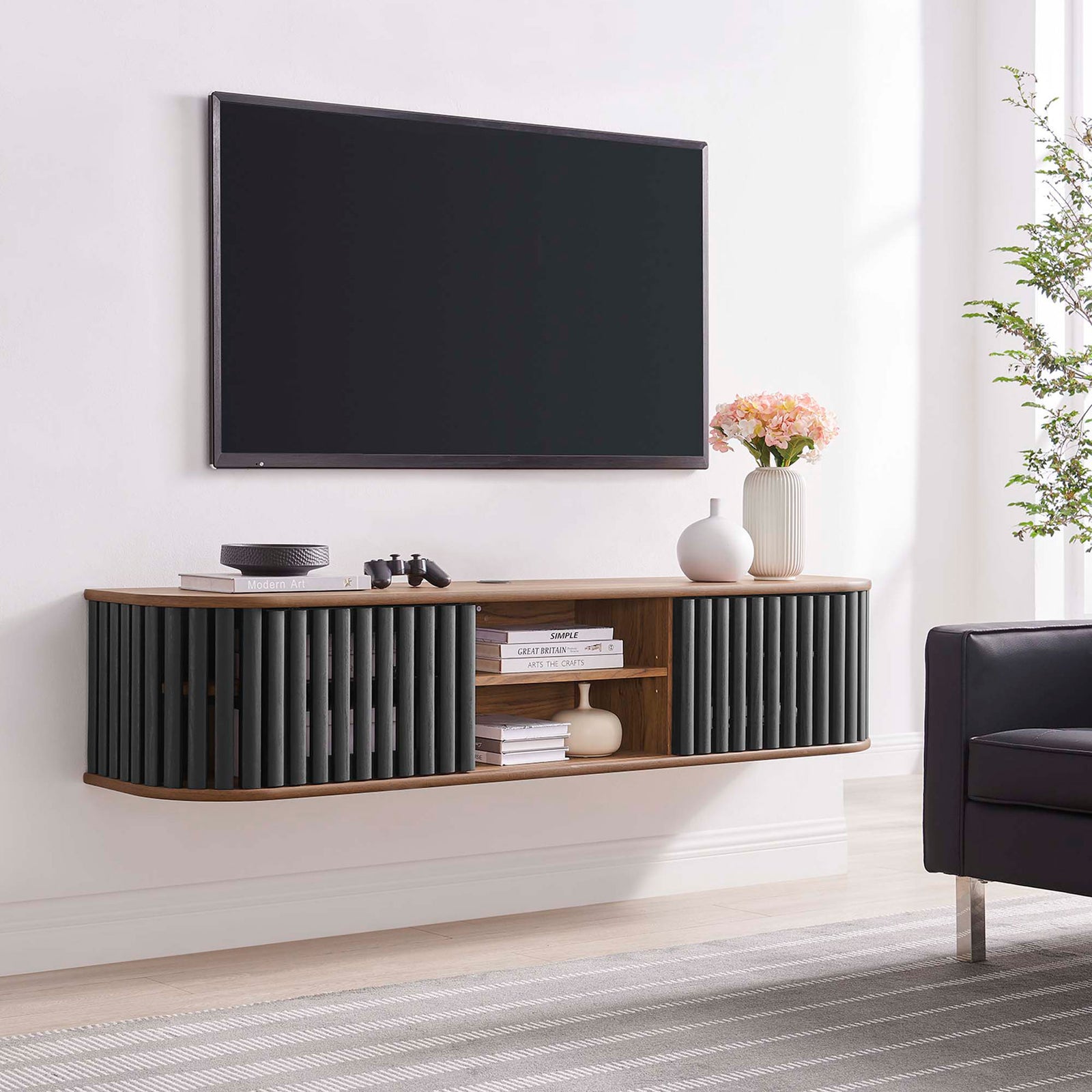 Walnut and black Fortitude wall mounted TV stand floating beneath a large screen in a contemporary living space || EEI-6528-WAL-BLK || front_room