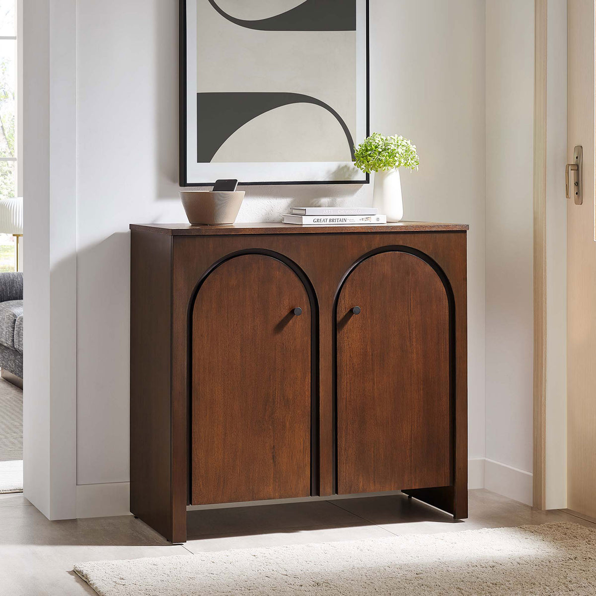 Walnut arched-door cabinet anchors a modern entryway with art, books, and greenery || EEI-6537-WAL || front_angle_room