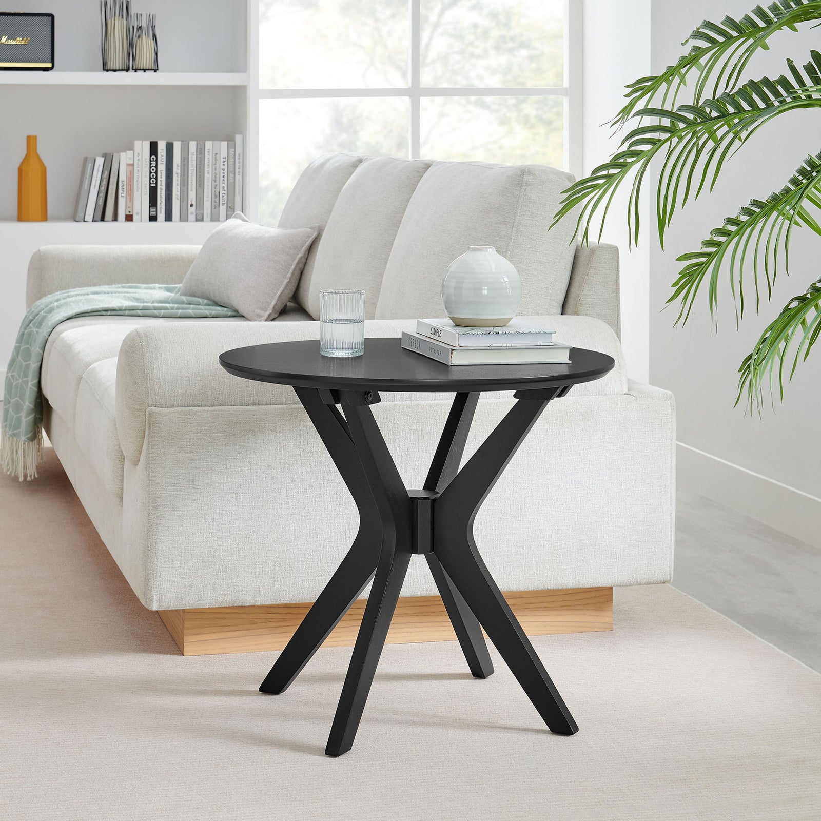 Black round side table complements a light sofa in a bright living room for a clean contemporary look || EEI-6558-BLK || front_angle_room