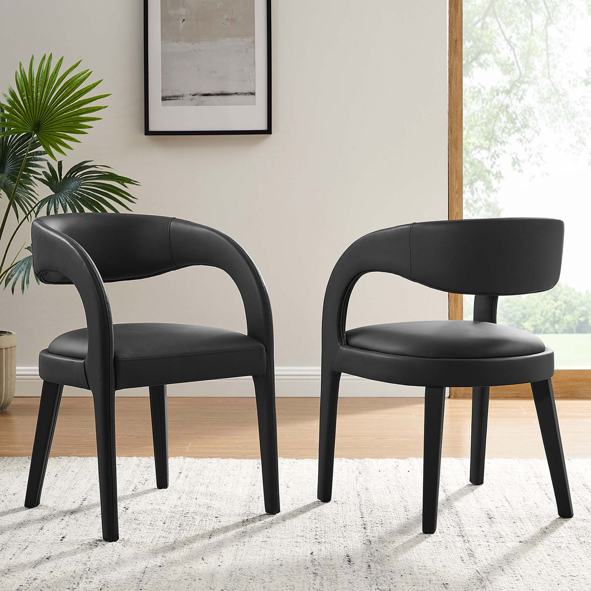 Pair of black vegan leather dining chairs in a bright room, adding sleek modern style around the table || EEI-6561-BLK || front_angle_multi_room
