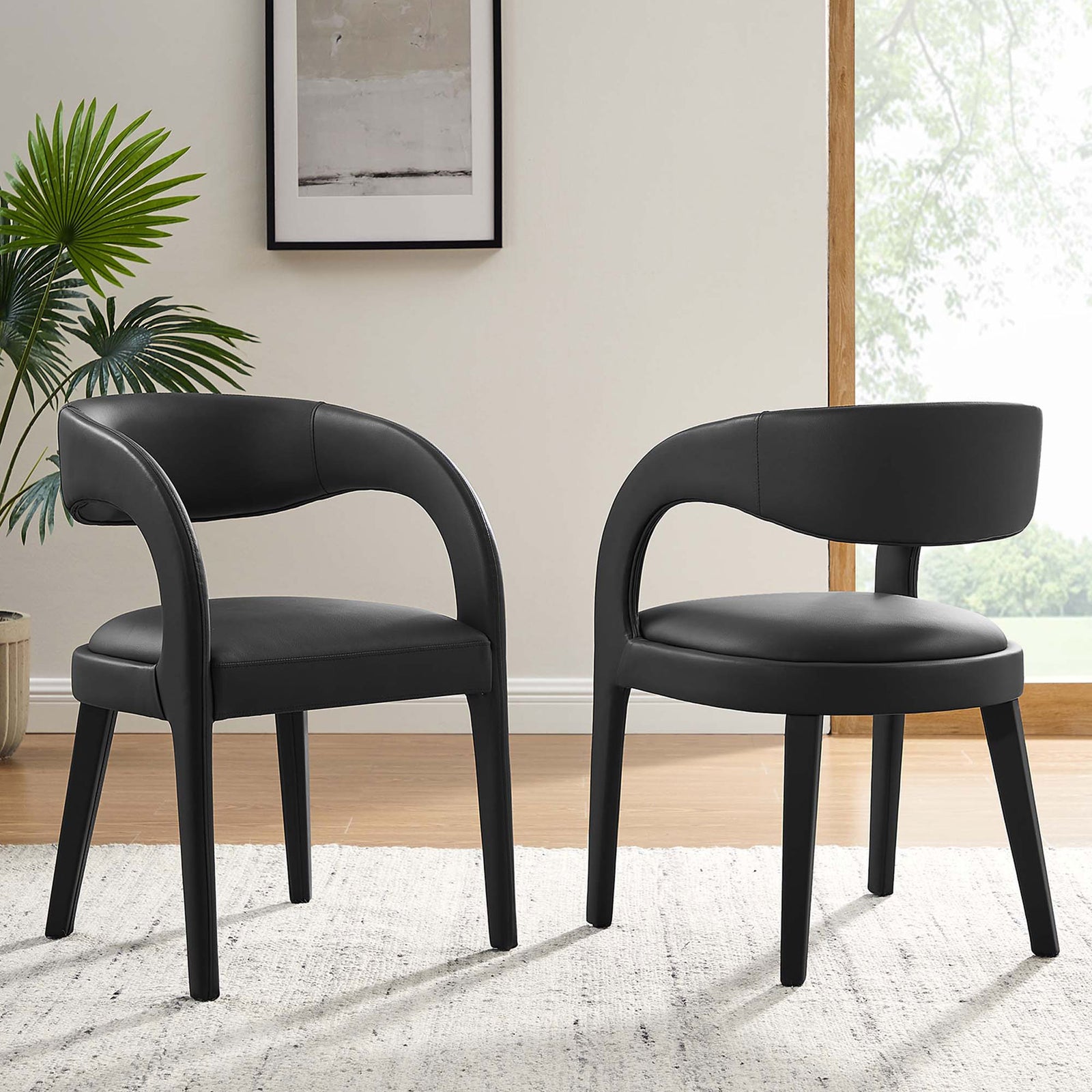 Pair of black vegan leather dining chairs in a bright room, adding sleek modern style around the table || EEI-6561-BLK || front_angle_multi_room