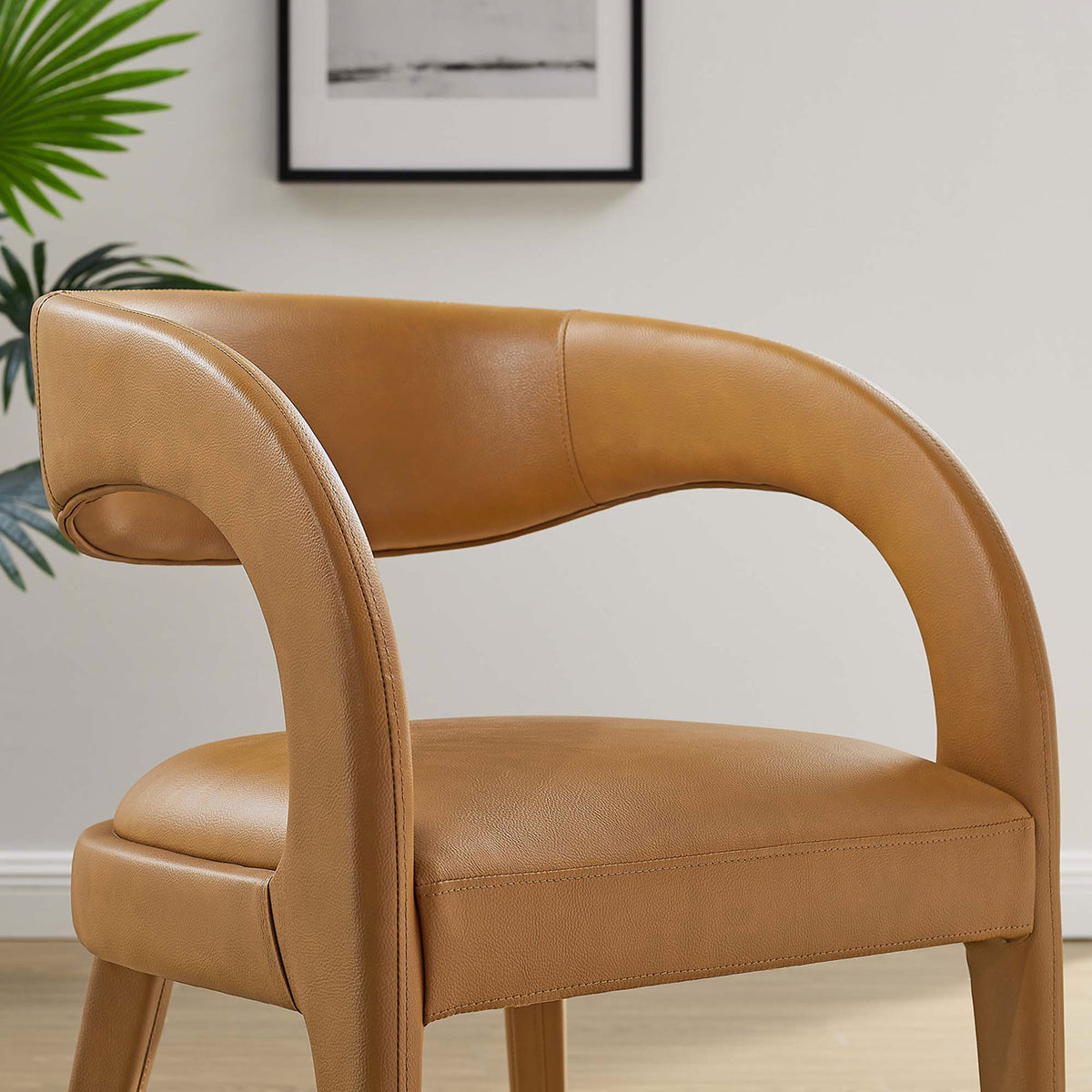 Tan vegan leather dining chair styled in a modern room with its curved backrest in focus || EEI-6561-TAN || detail_room