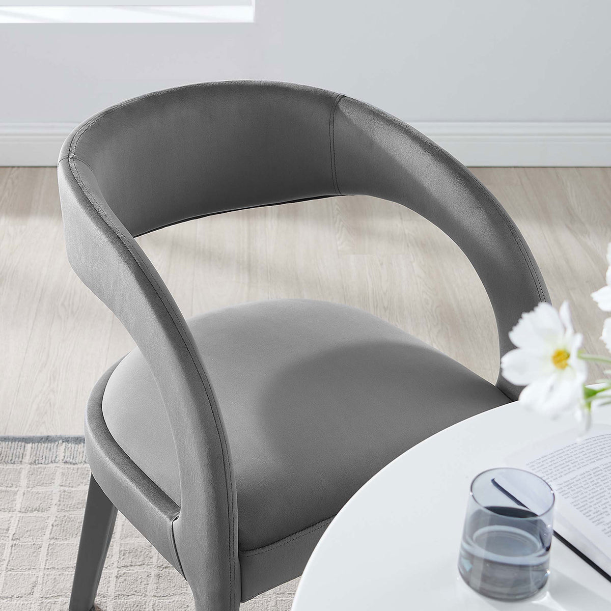 Gray velvet dining chair paired with a white table, adding soft curves and comfort to a sunlit dining nook || EEI-6563-GRY || detail_room