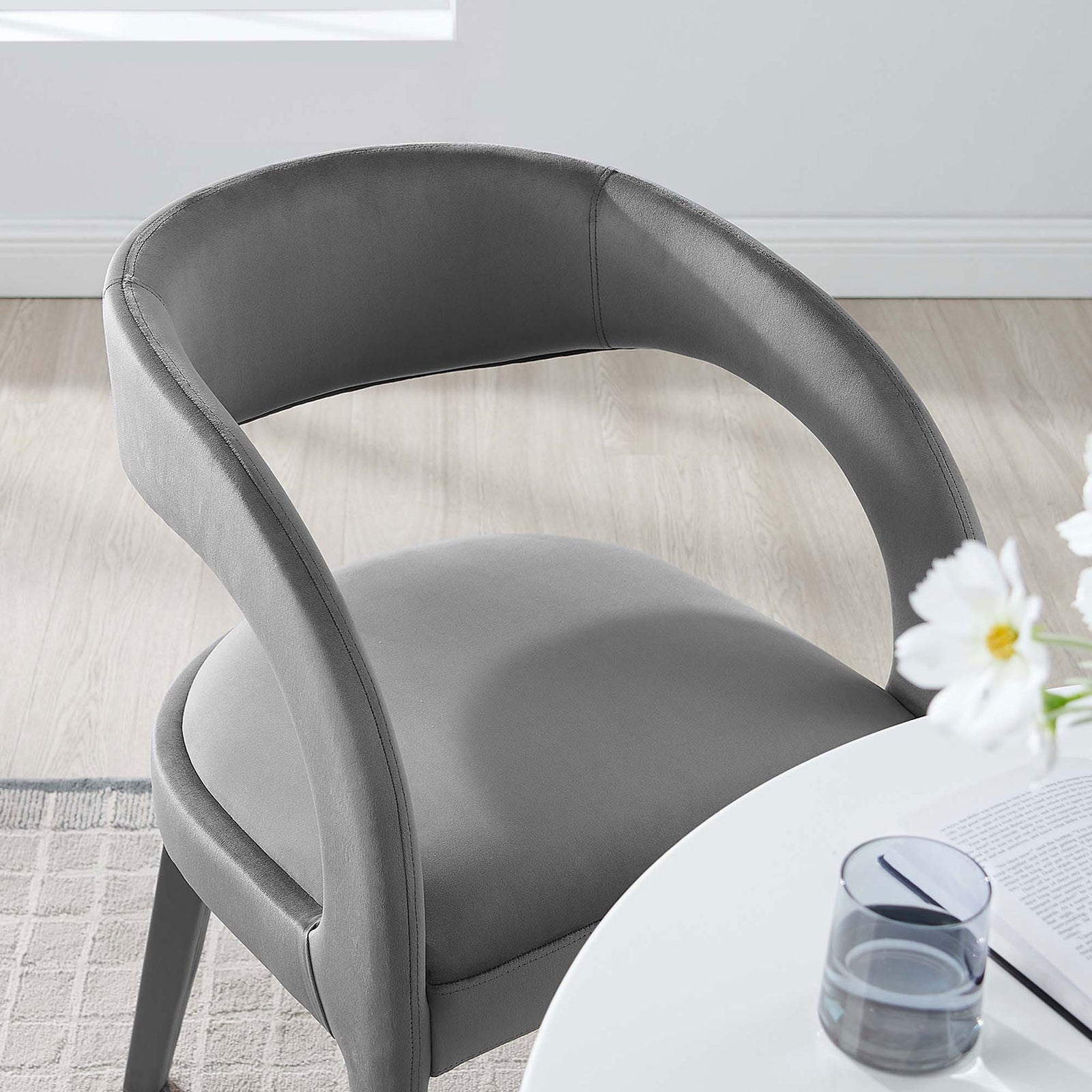 Gray velvet dining chair paired with a white table, adding soft curves and comfort to a sunlit dining nook || EEI-6563-GRY || detail_room