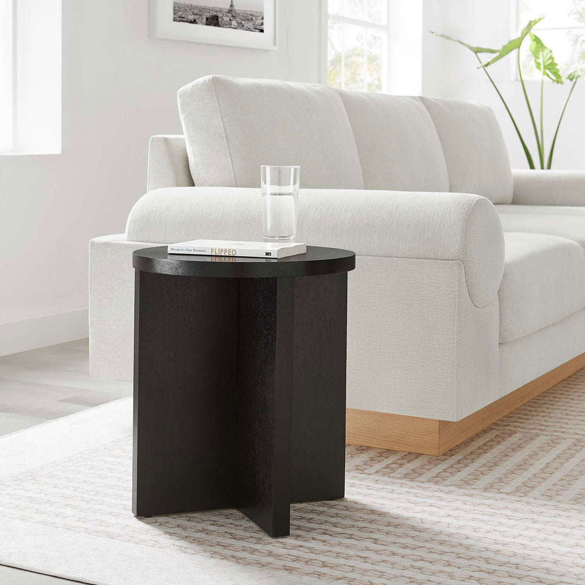 Black round side table beside a plush white sofa, perfect for holding drinks, books, and decor || EEI-6579-BLK || front_room