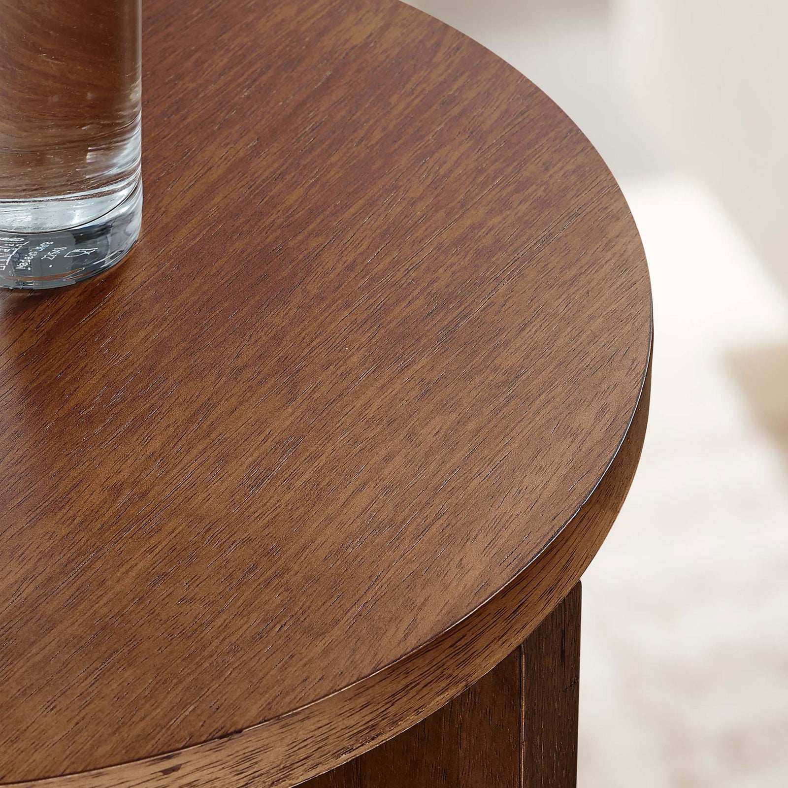 Walnut tabletop styled with a glass of water against a softly lit living room backdrop || EEI-6579-WAL || detail_room