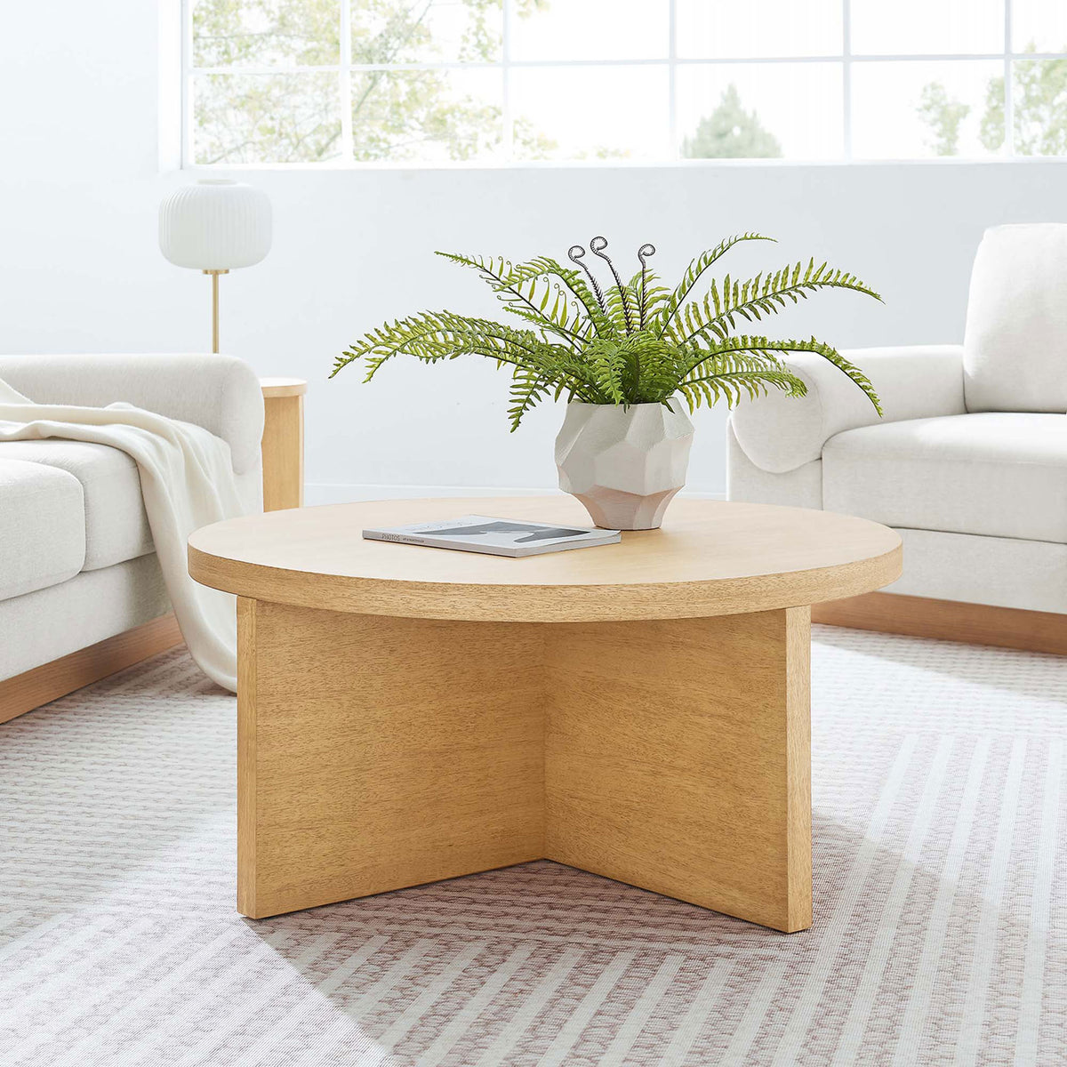 Versatile round coffee table anchors a light, airy living room with natural warmth || EEI-6580-NAT || front_angle_room