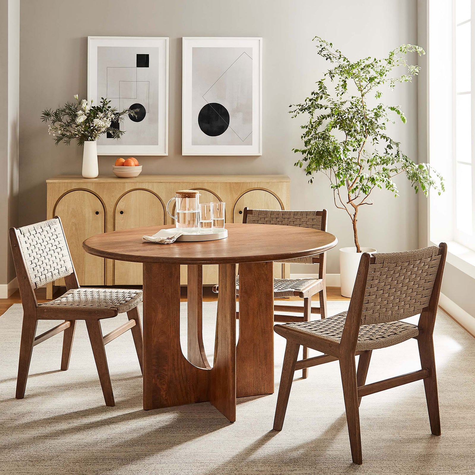 Round walnut dining table styled in a bright modern dining room with four coordinating chairs. || EEI-6592-WAL || front_angle_room