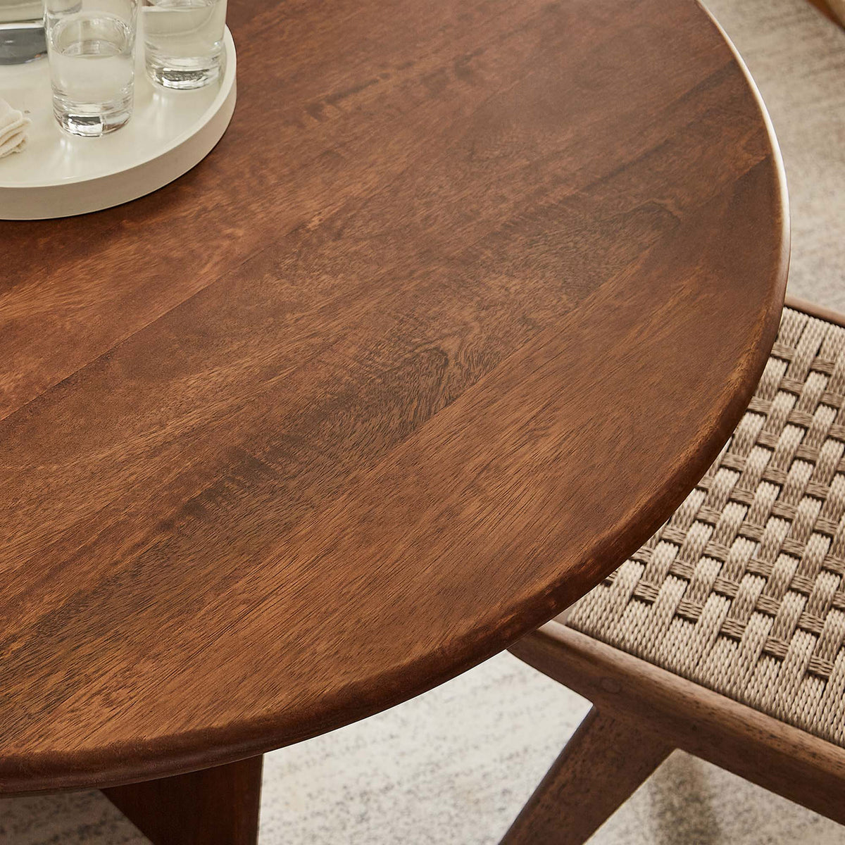 Lifestyle close up of the walnut tabletop paired with a woven dining chair in a warm neutral room. || EEI-6592-WAL || detail_room