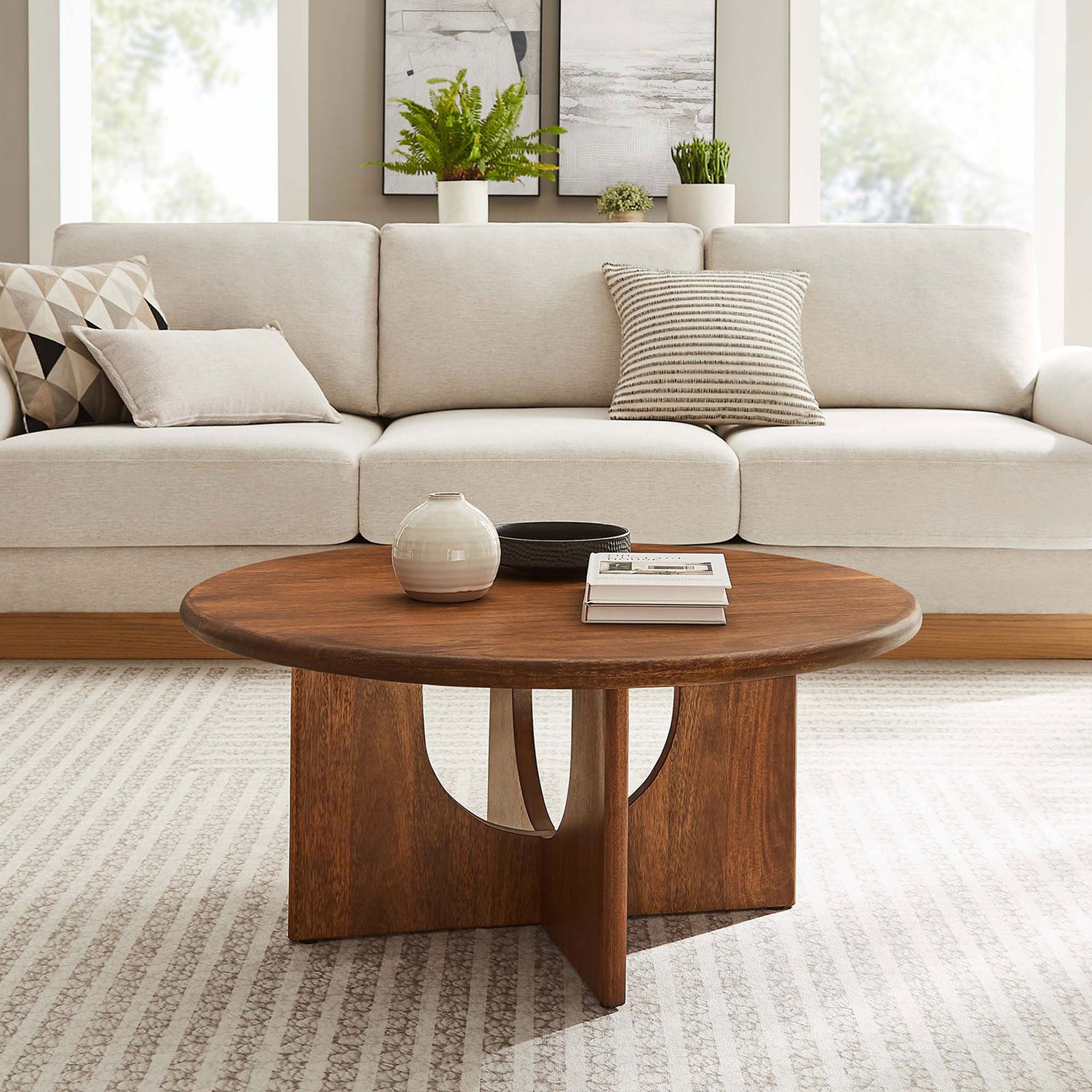 Warm walnut coffee table anchors the space with a sculptural pedestal base and round top || EEI-6594-WAL || front_angle_room
