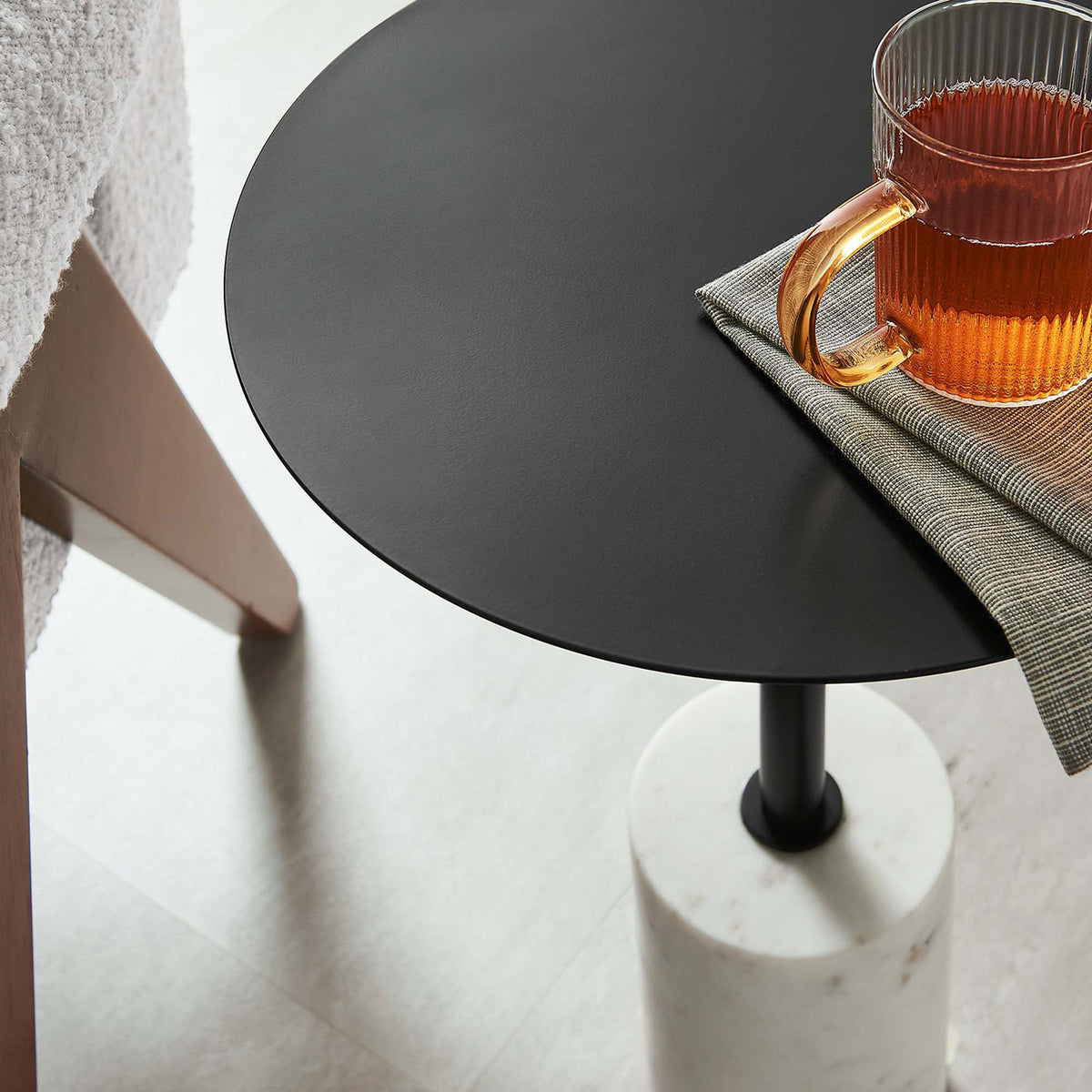 Lyric side table styled with a warm drink beside seating, showcasing the slim pedestal and marble base || EEI-6605-WHI-BLK || detail_room