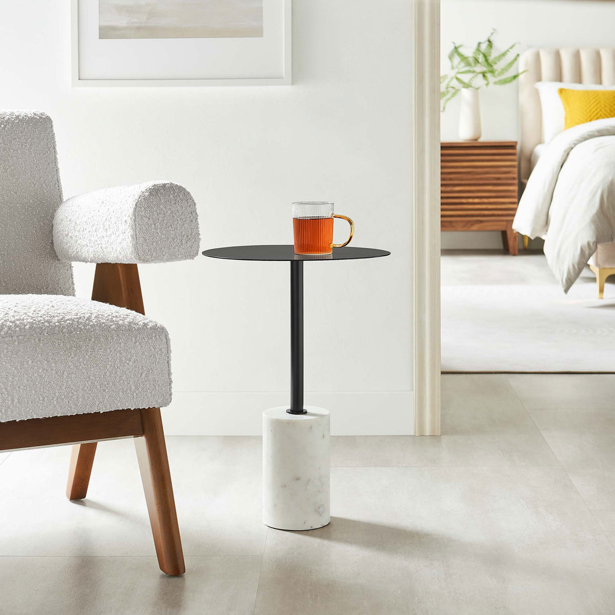 Lyric round side table in a modern bedroom setting beside an accent chair and bed || EEI-6605-WHI-BLK || front_angle_room