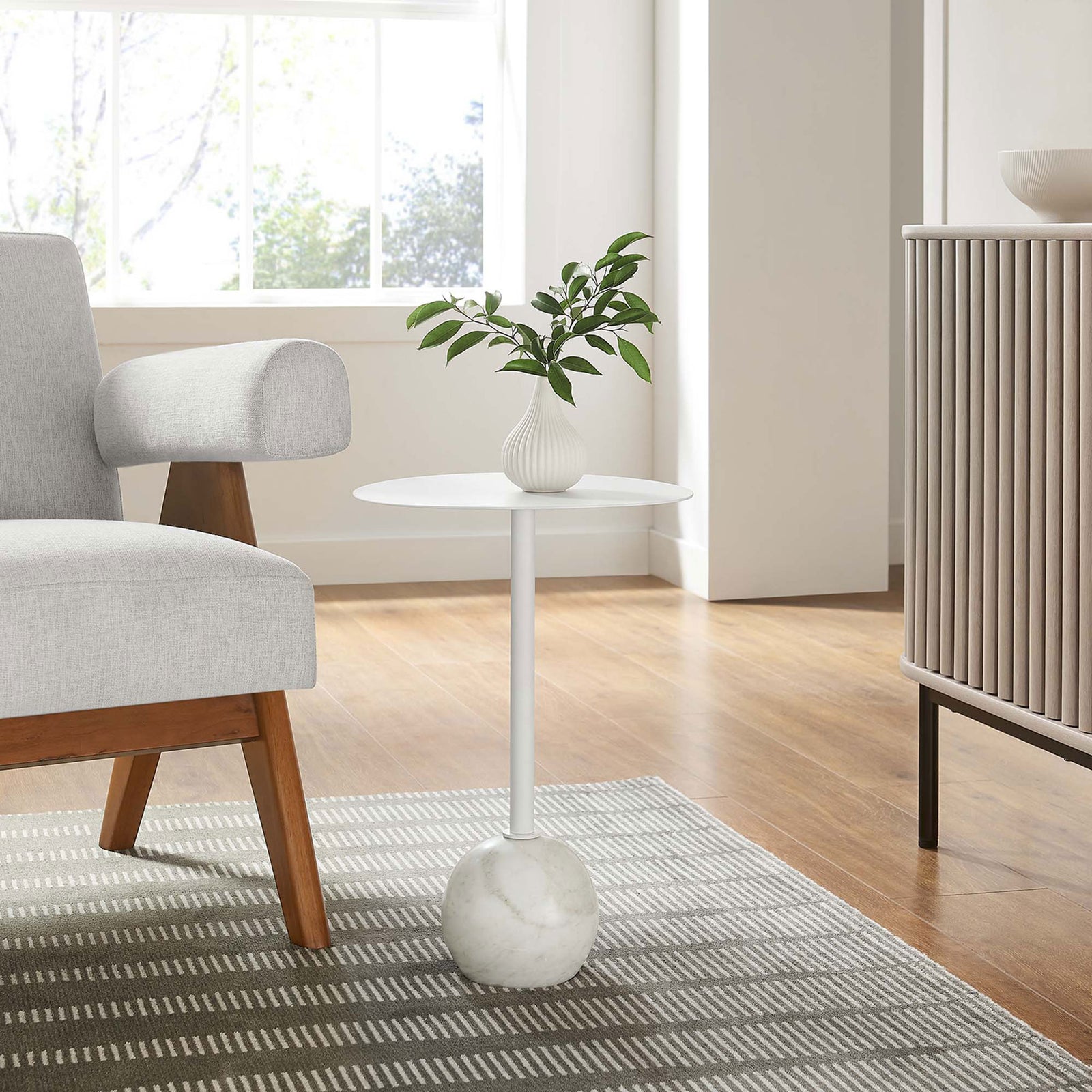 Round white side table with marble base accenting a modern living room next to a mid century chair || EEI-6606-WHI-WHI || front_angle_room