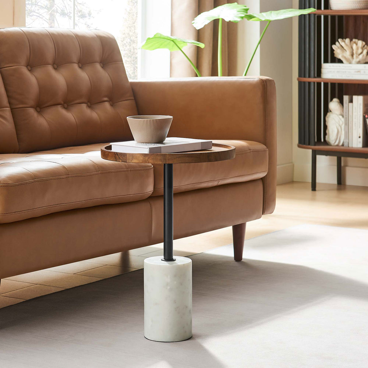 Round acacia side table with marble base styled beside a tan sofa in a bright modern living room || EEI-6607-WHI-LOC || front_angle_room