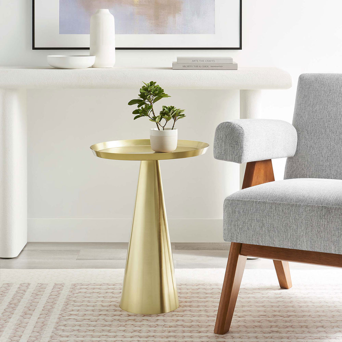 Maren brass round side table accenting a contemporary living room beside a gray chair and soft textured rug || EEI-6608-BRA || front_angle_room