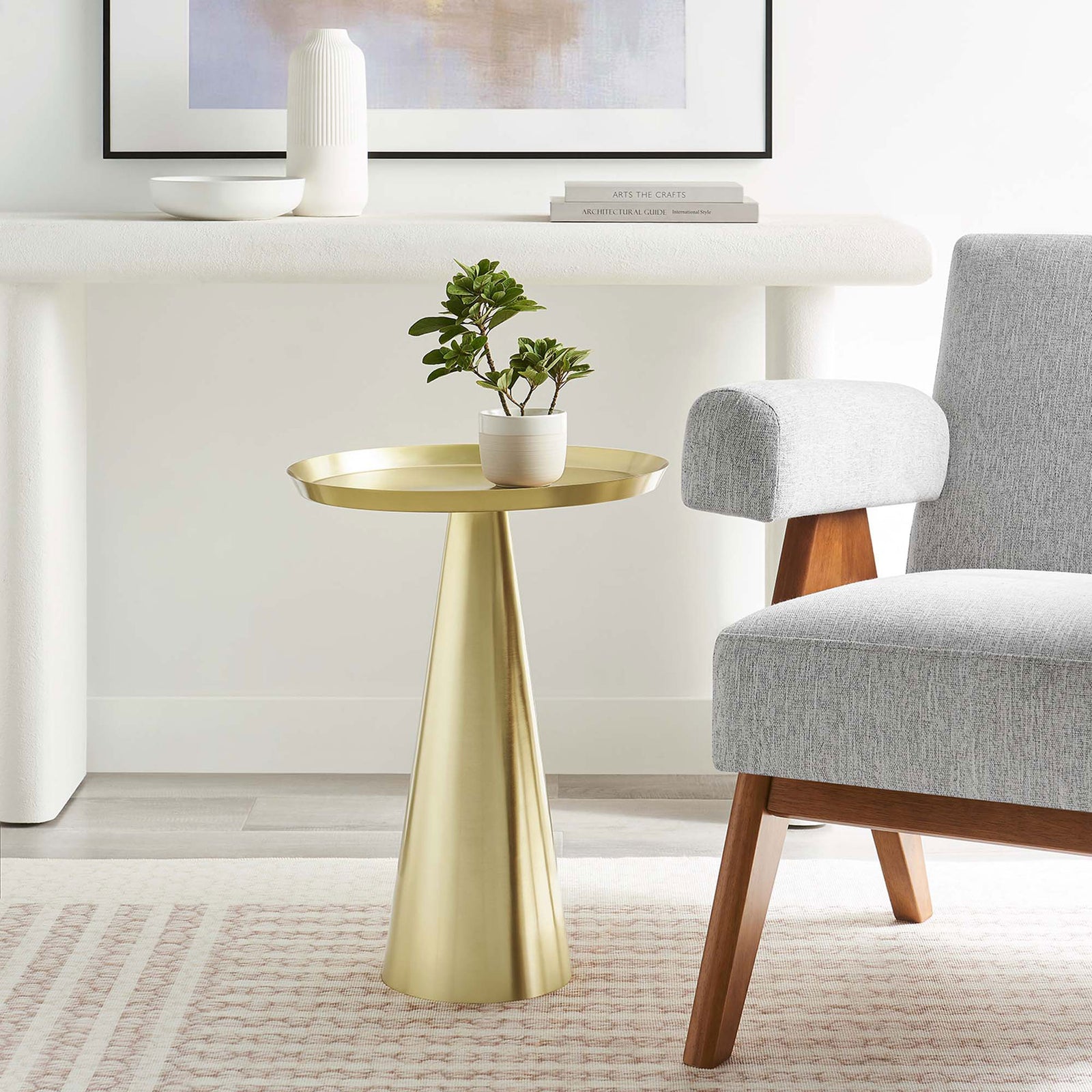 Maren brass round side table accenting a contemporary living room beside a gray chair and soft textured rug || EEI-6608-BRA || front_angle_room