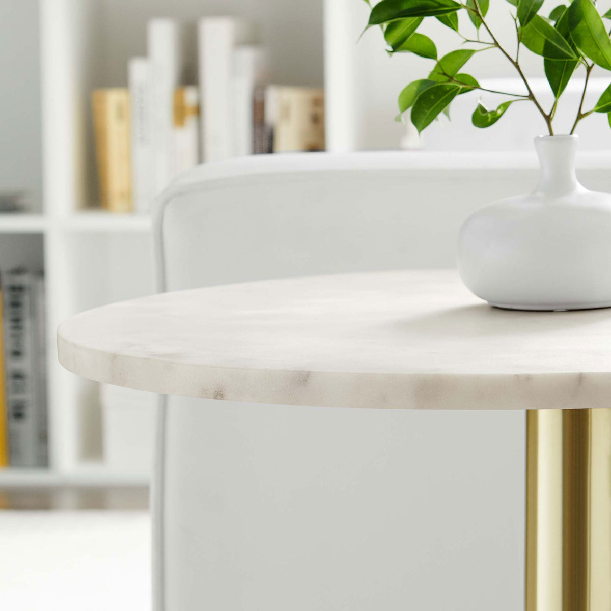 White marble tabletop framed by a brass pedestal base complements modern seating and greenery in a bright living space || EEI-6609-BRA-WHI || detail_room