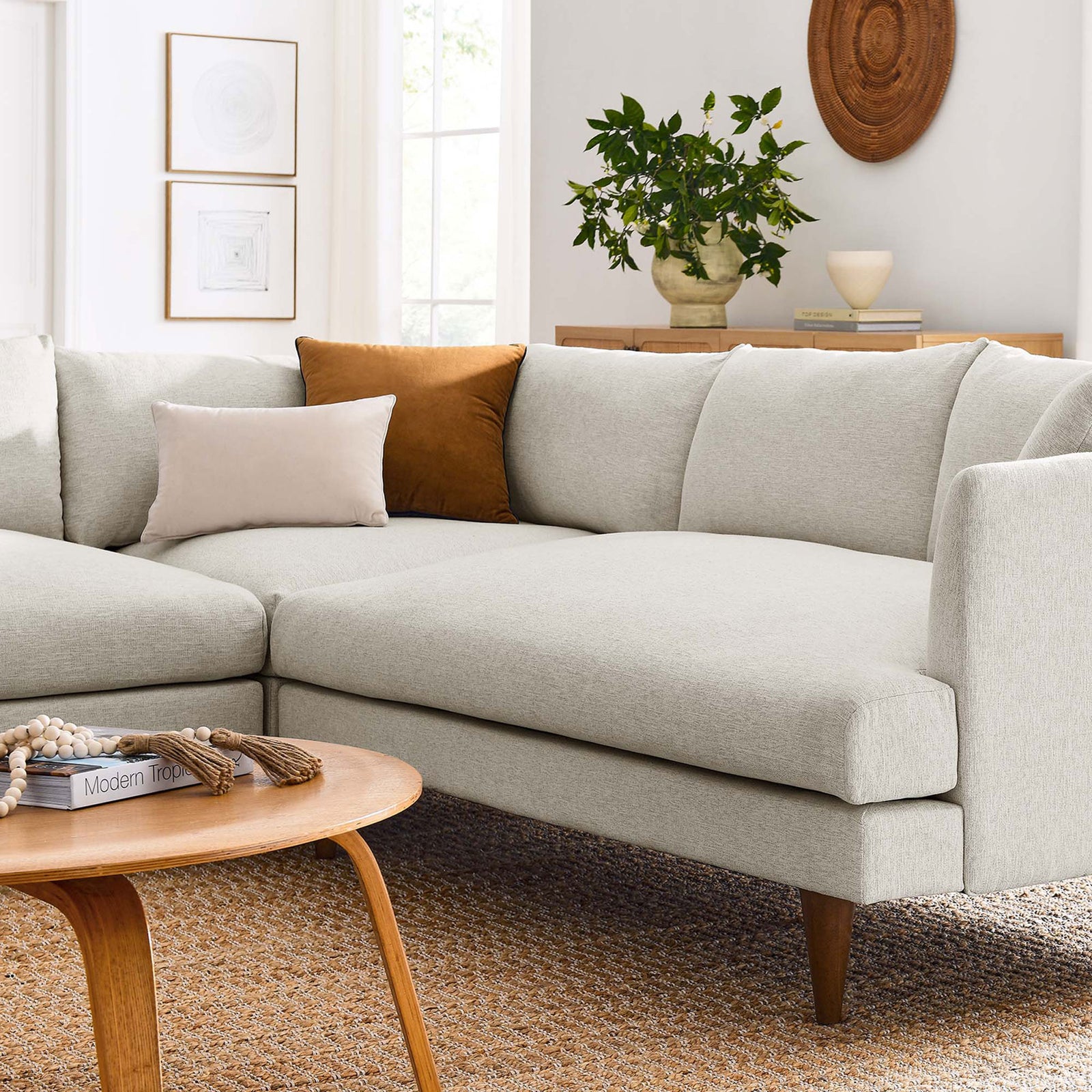 Cozy corner of the ivory sectional styled with layered throw pillows, a wood coffee table, and textured rug || EEI-6613-HEI || detail_room