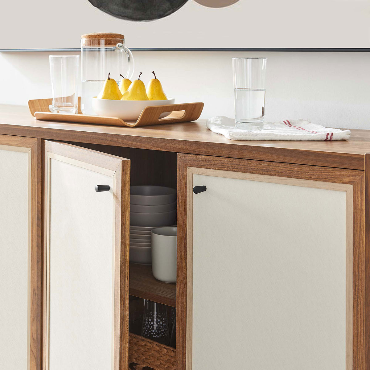 Styled sideboard in use with doors open to display neatly organized dishes and baskets. || EEI-6616-WAL || storage_open_room