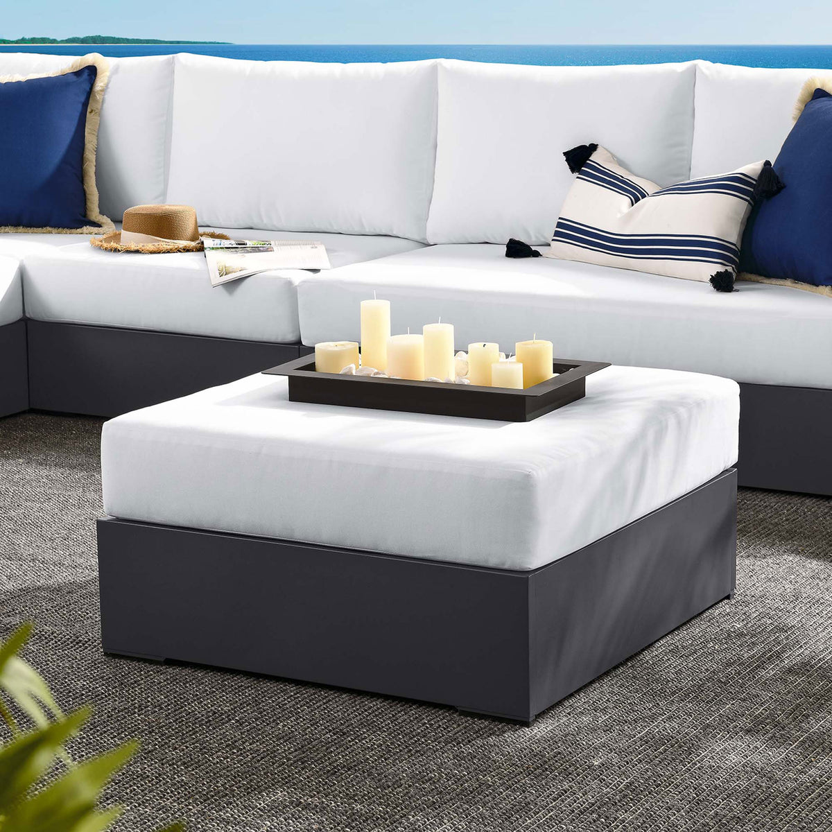 Tahoe white ottoman anchors a coastal-inspired outdoor sectional styled with navy and striped pillows || EEI-6627-GRY-WHI || front_angle_room