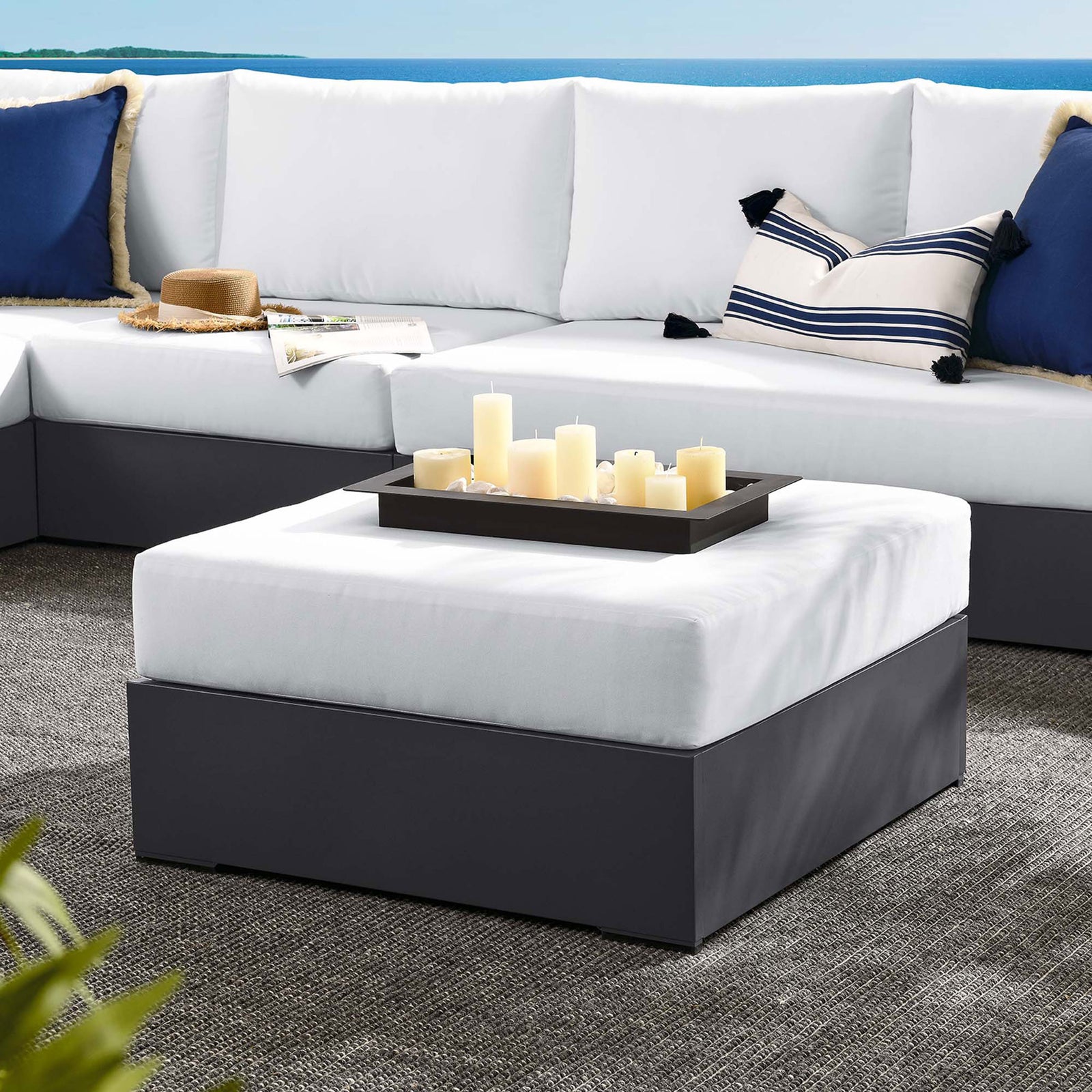 Tahoe white ottoman anchors a coastal-inspired outdoor sectional styled with navy and striped pillows || EEI-6627-GRY-WHI || front_angle_room
